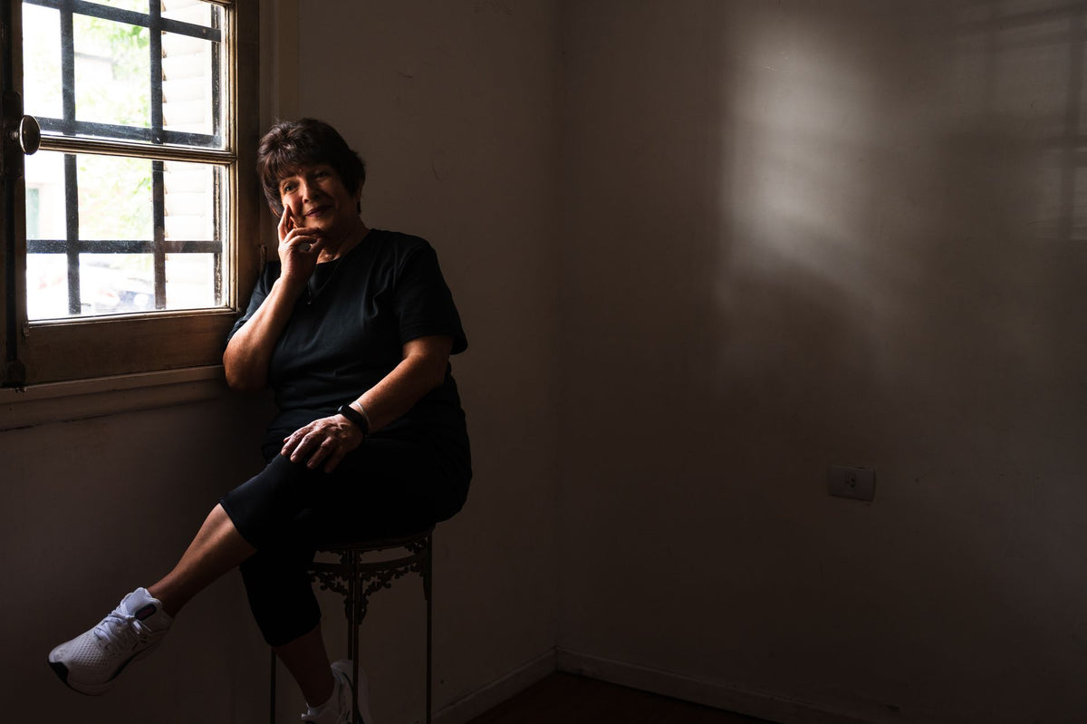 Frau von hinten in heller Küche am Fenster, Tasse in der Hand