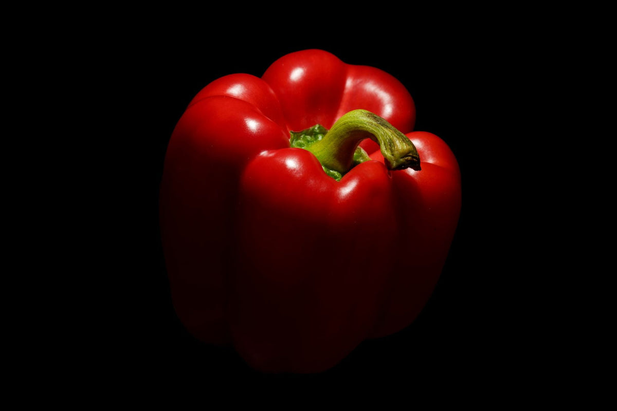 Rote Paprika und Zitronen auf einem Holztisch, daneben ein Messer und ein Schneidebrett