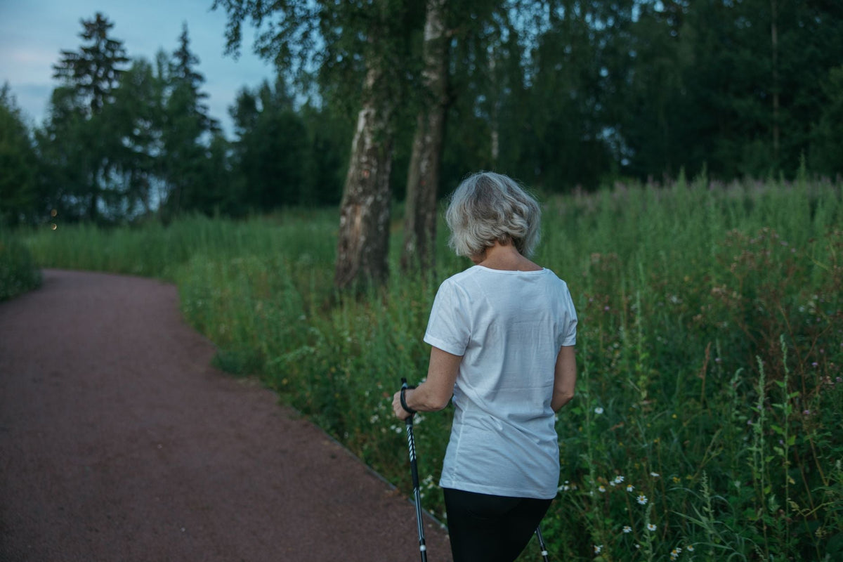 Ältere Frau geht einen Waldweg entlang