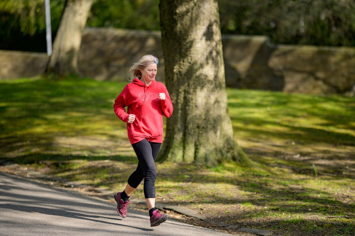Frau von hinten beim Joggen auf einem herbstlichen Parkweg